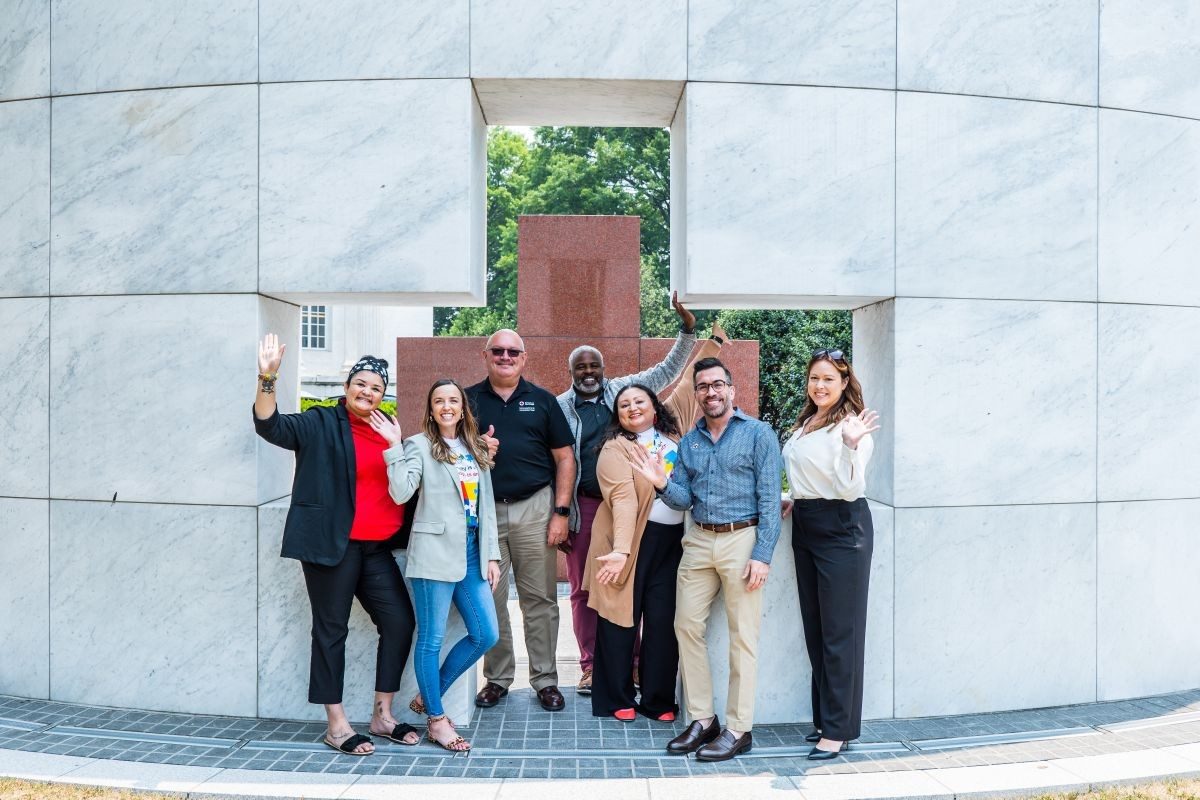 a group of Red Crossers stand in front of a Red Cross relief sculpture