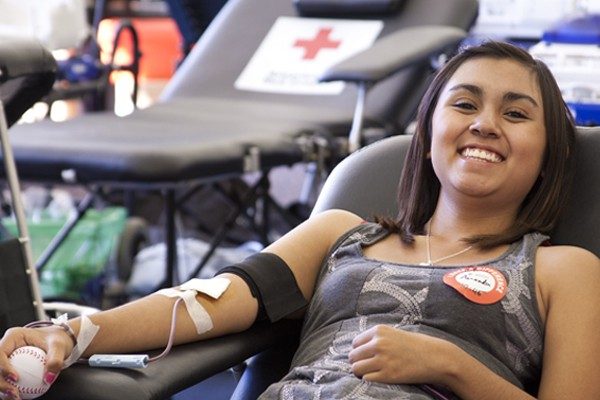 Person in chair donating blood and smiling.