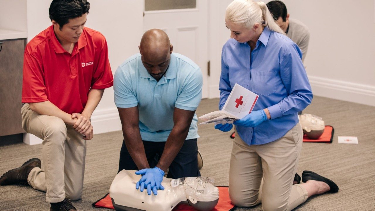 a Red Cross instructor teaches a student how to do CPR on a mannekin