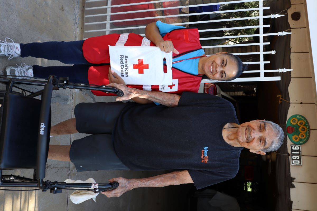 Hombre y mujer sonriendo sosteniendo la bolsa de la cruz roja.