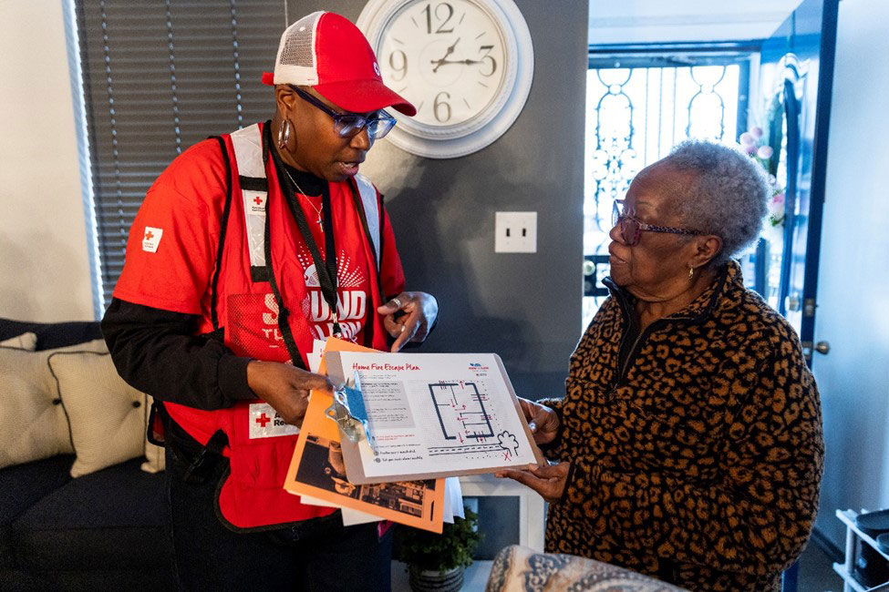 Red Cross volunteer showing fire escape route plans to a resident.
